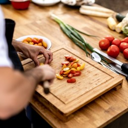 a person cutting up vegetables on a cutting board